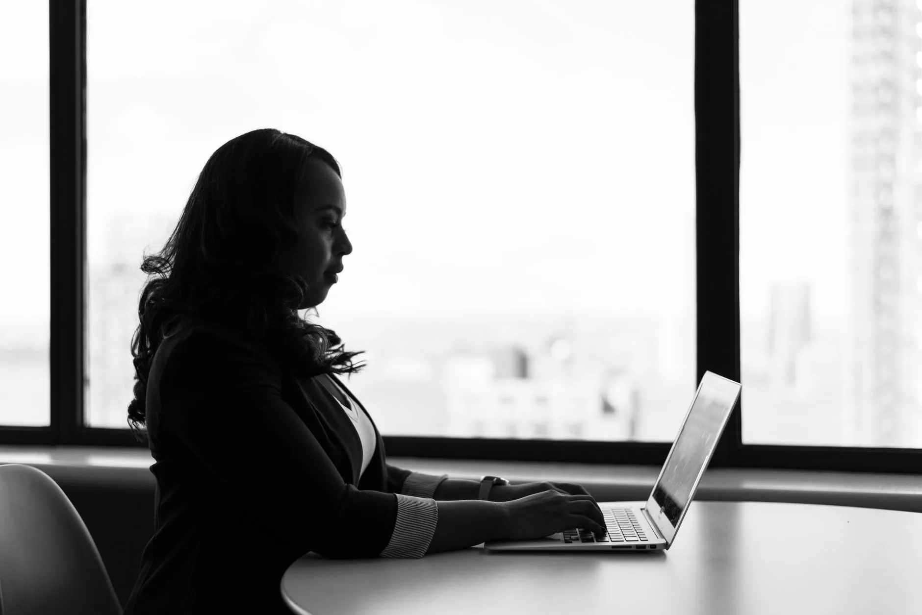 Geração de leads B2B e B2C — Imagem em preto e branco de uma mulher trabalhando em seu laptop em um ambiente de escritór