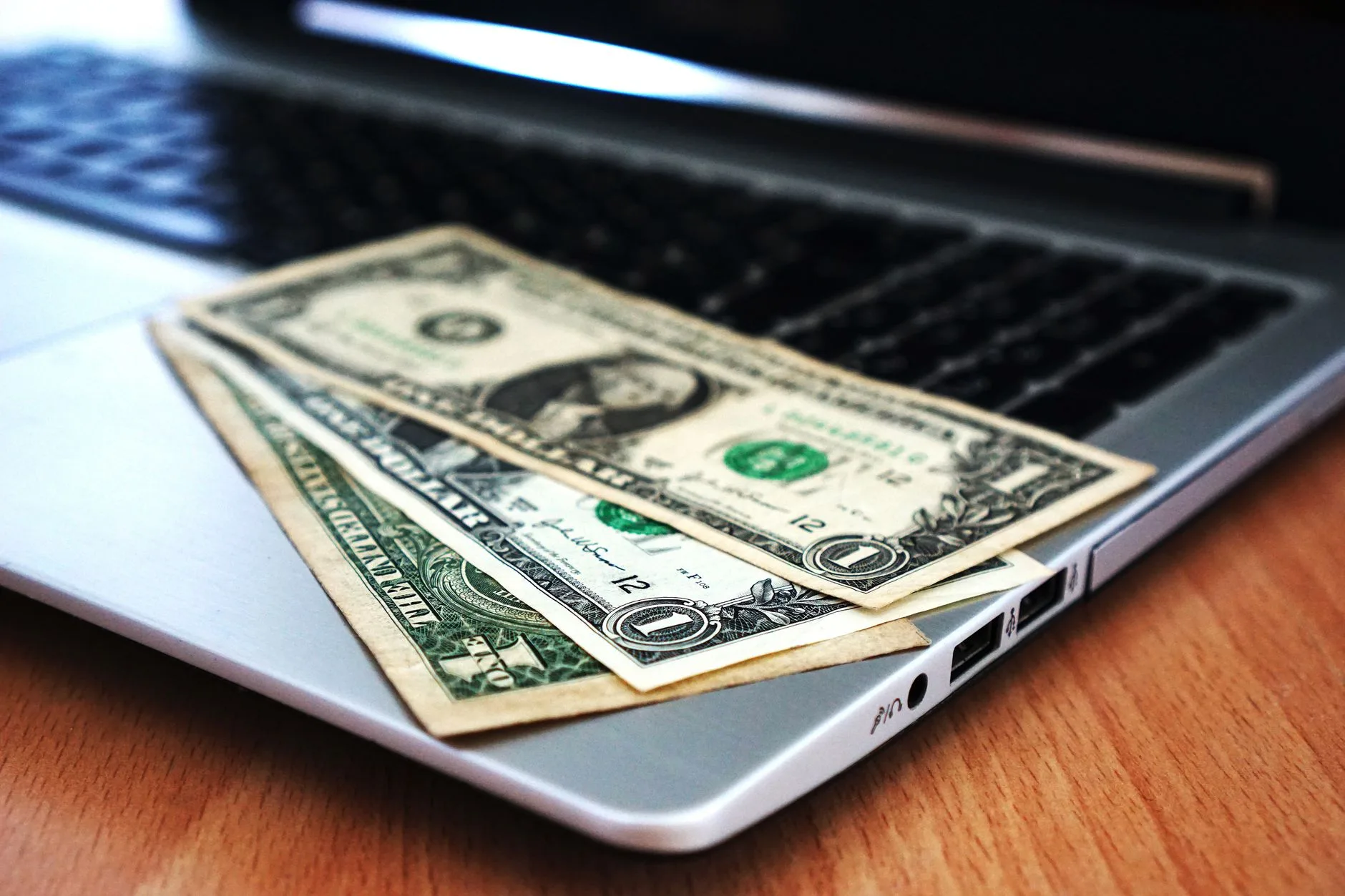 Taxa de conversão de leads ideal — Close-up de notas de dólar americano colocadas em um laptop simbolizando finanças dig